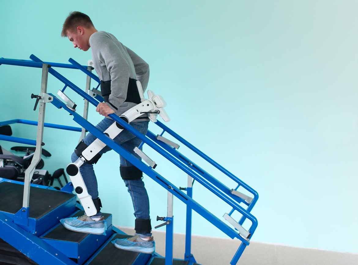 Человек поднимается по импровизированной лестнице в реабилитационном экзоскелете
